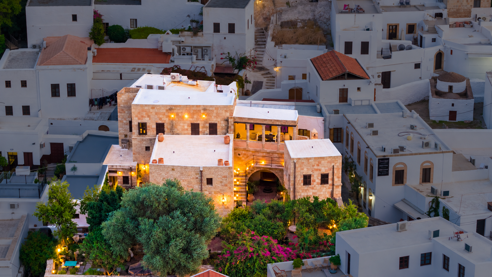 Vasilikos Mansion illuminated at dusk among the whitewashed houses of Lindos
